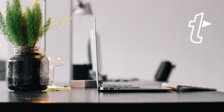 Minimal desk with a laptop, keyboard and potted plant, with the TextExpander logo, suggesting a distraction-free writing space