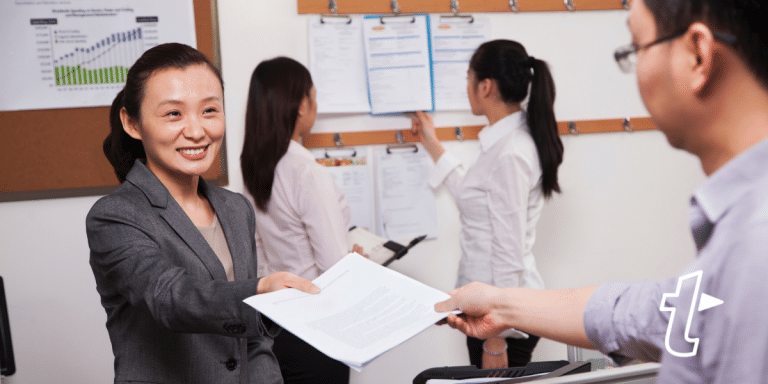 smiling lady handing paper to man