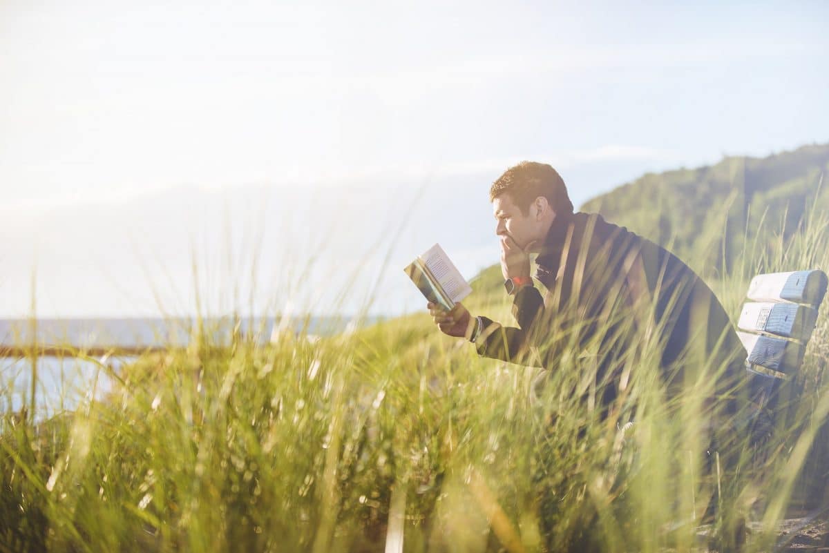 man sitting on bench reading