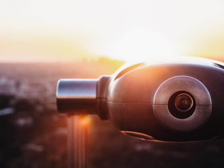 Coin-operated viewing binoculars overlooking a city at sunset