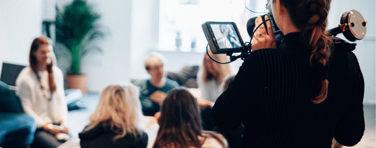 Woman uses camera to record team in a meeting.