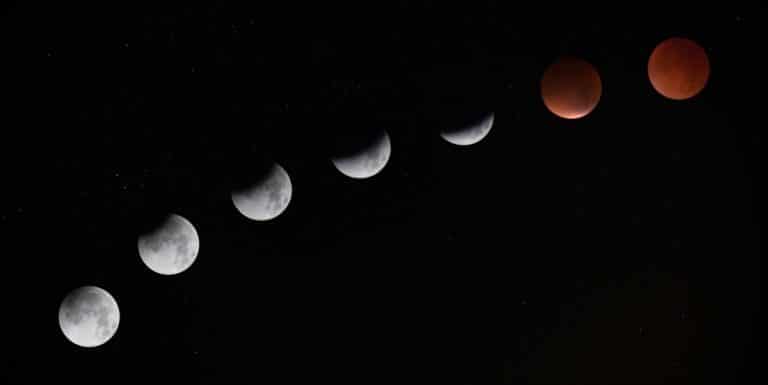Sequence of moon phases during a lunar eclipse across a night sky, representing stages of a life cycle