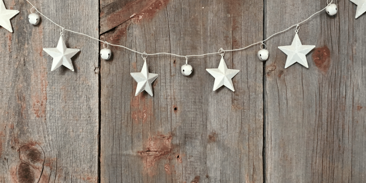 White star garland with bells hanging against a weathered wooden wall