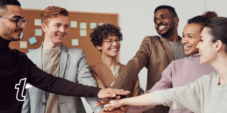 Diverse group of smiling coworkers stacking hands in the middle, with the TextExpander logo