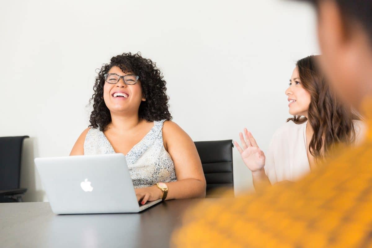 Motivated female recruiter tilts smiles while typing on her keyboard