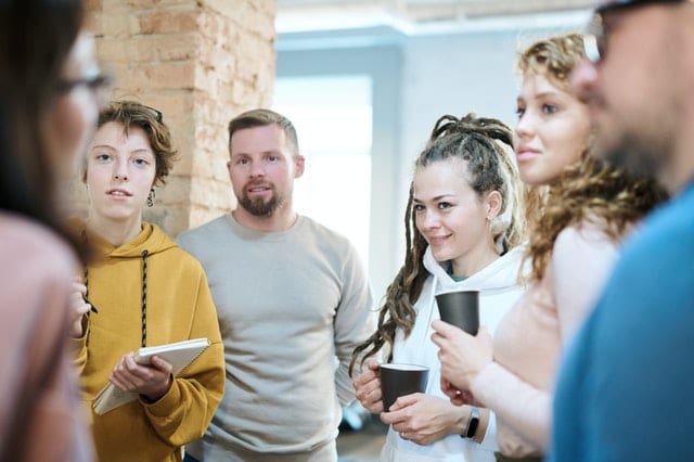 A team of male and female recruiters have a standing check-in meeting