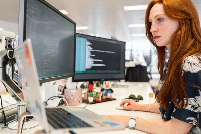 Motivated female recruiter sits in front of screens using various recruiting tools.