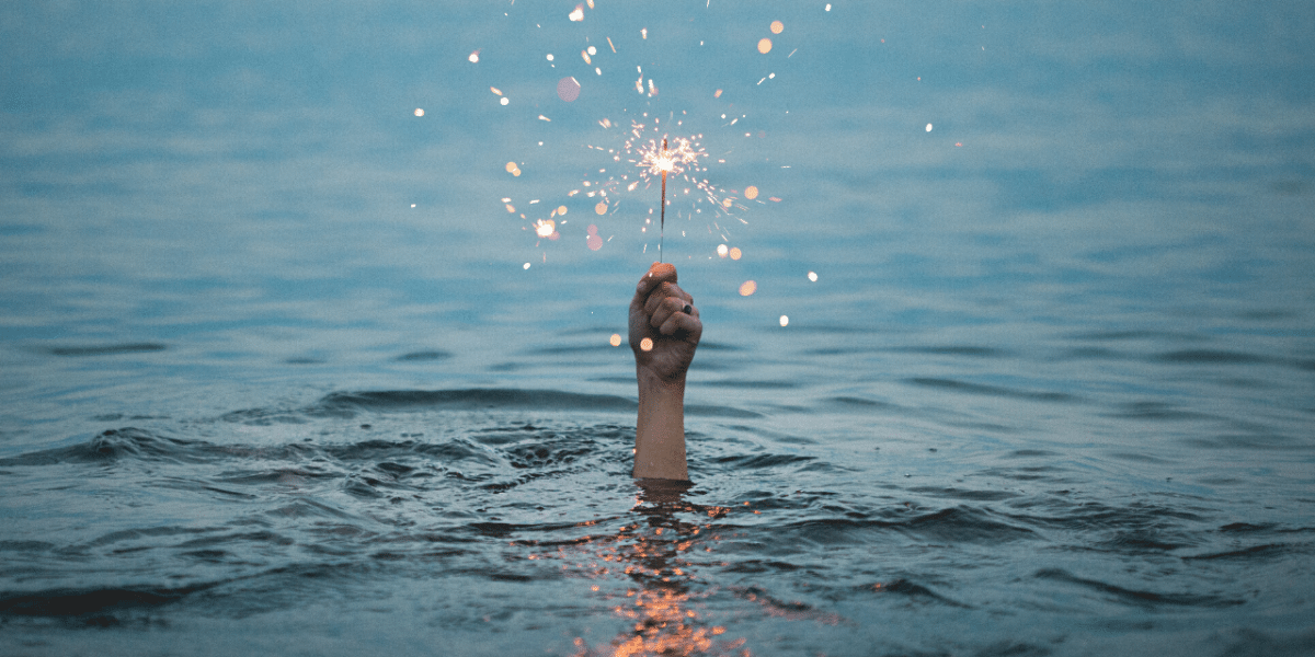 Hand holding sparkler in the water