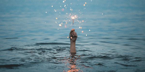 Hand holding sparkler in the water