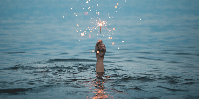 Hand holding sparkler in the water