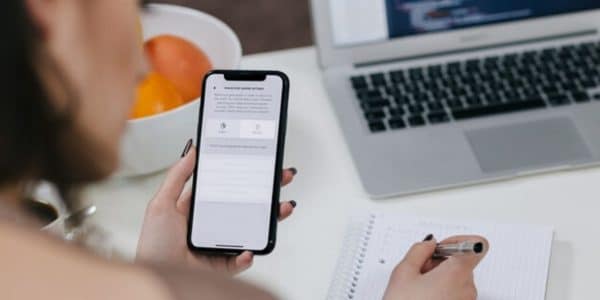Recruiter holding a cell phone with a notebook in the background during the text recruiting process