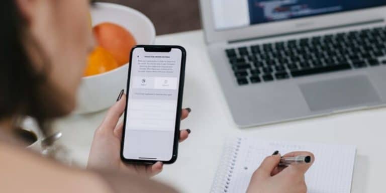 Recruiter holding a cell phone with a notebook in the background during the text recruiting process