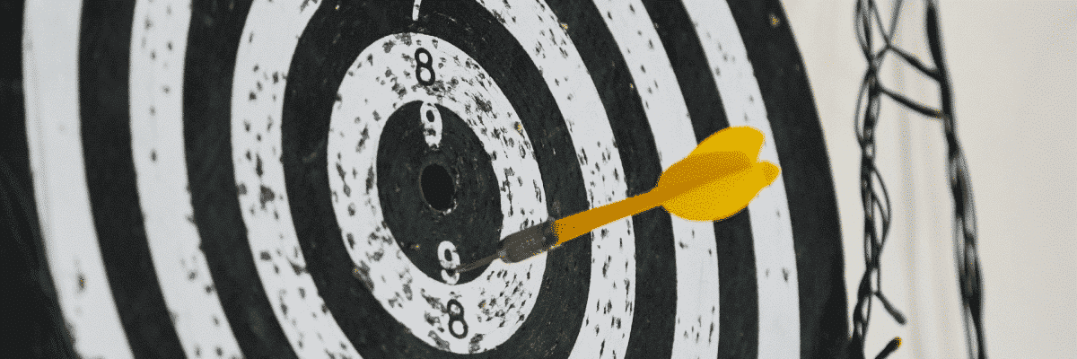 Yellow dart stuck in a black and white dartboard just off the bullseye