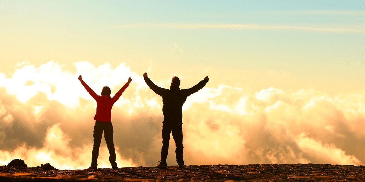 two people celebrating against a sunset
