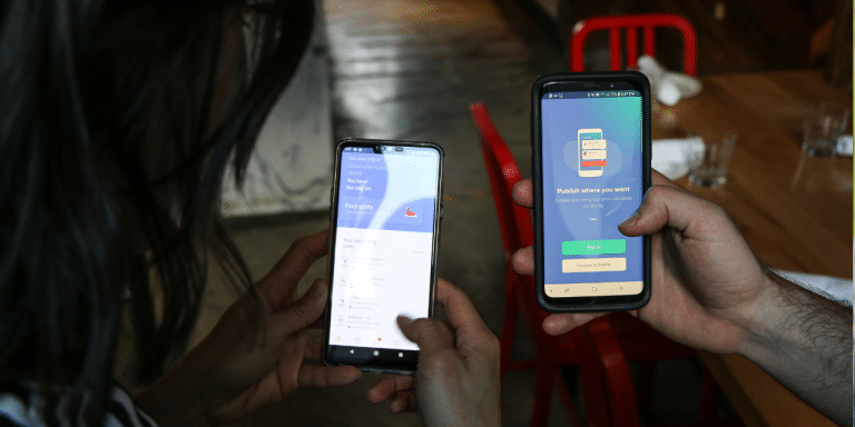 Two people holding smartphones showing app screens across a restaurant table