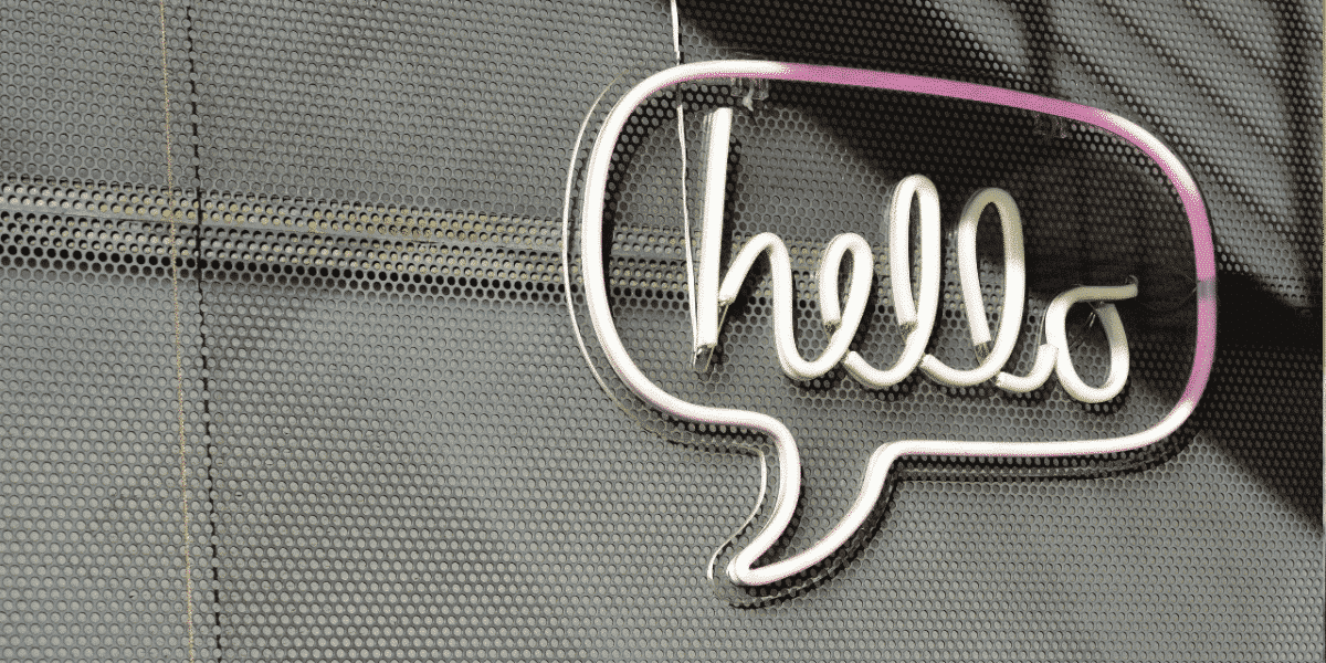 Neon hello sign inside a speech bubble on a perforated metal wall