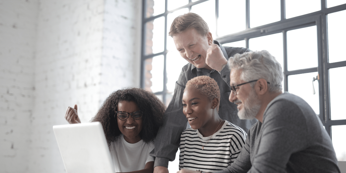 a team smiling looking at a laptop