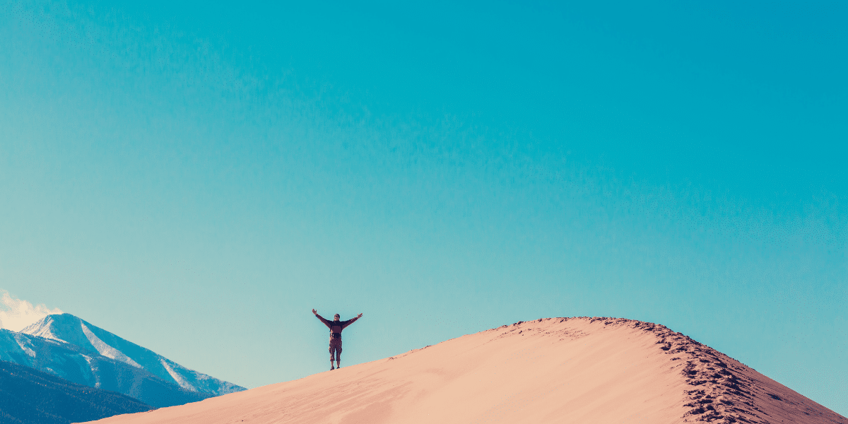 person on top of mountain with arms raised