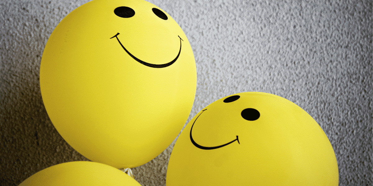 Yellow smiley-face balloons against a textured grey wall