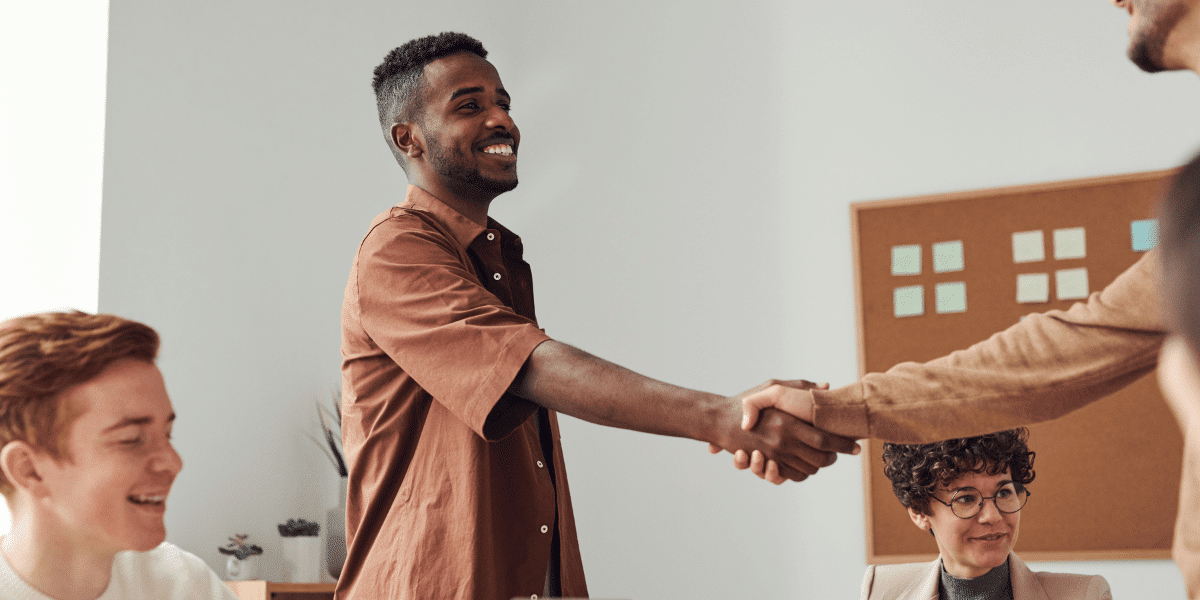 two people shaking hands over desk