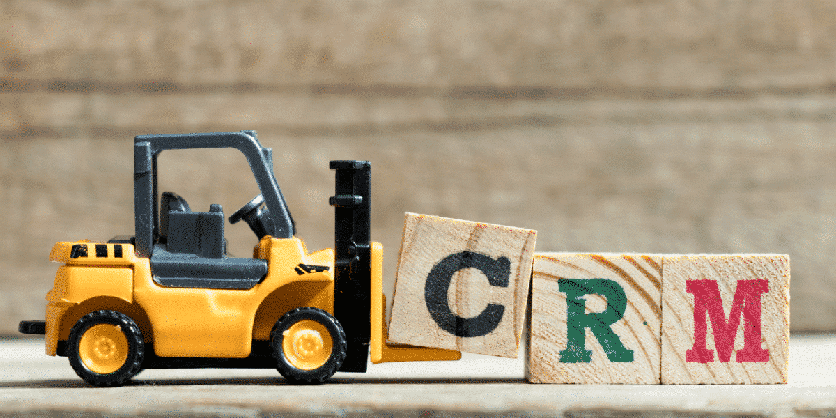 toy digger carrying blocks that spell CRM