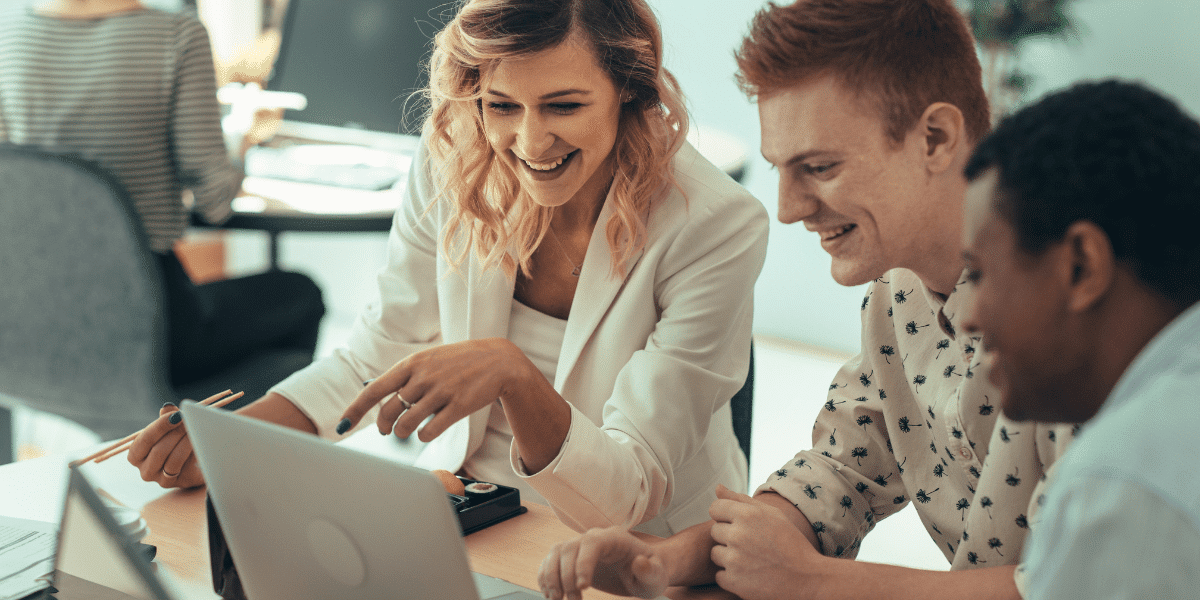 team smiling at a laptop