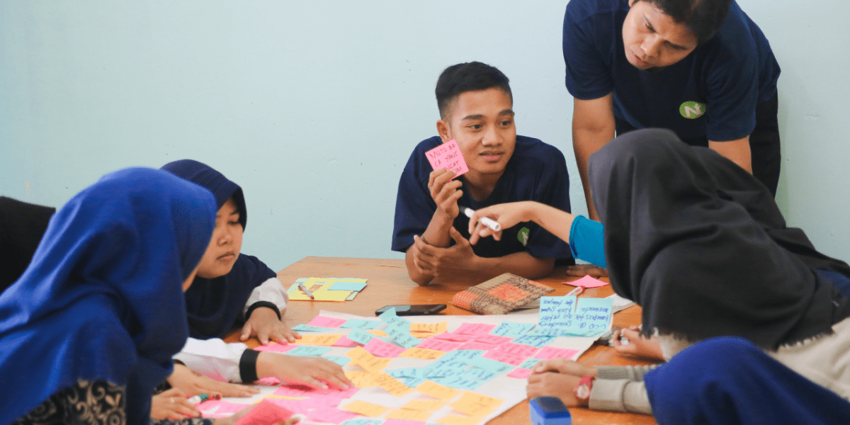 Young people working together at a table covered in colorful sticky notes during a brainstorming session