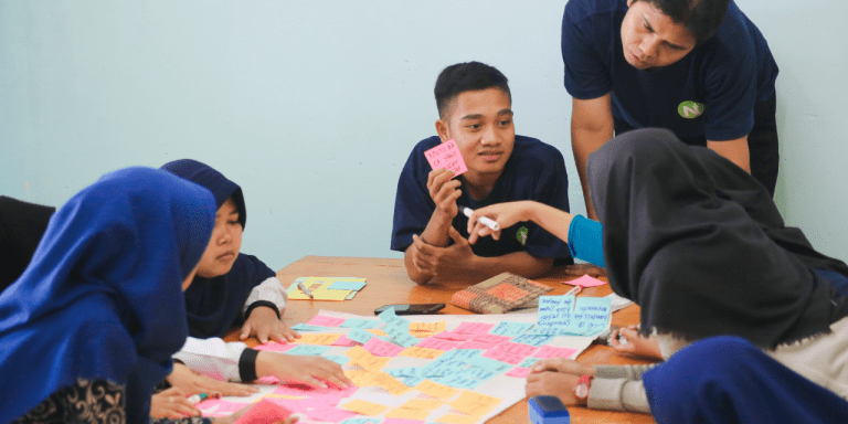 Young people working together at a table covered in colorful sticky notes during a brainstorming session
