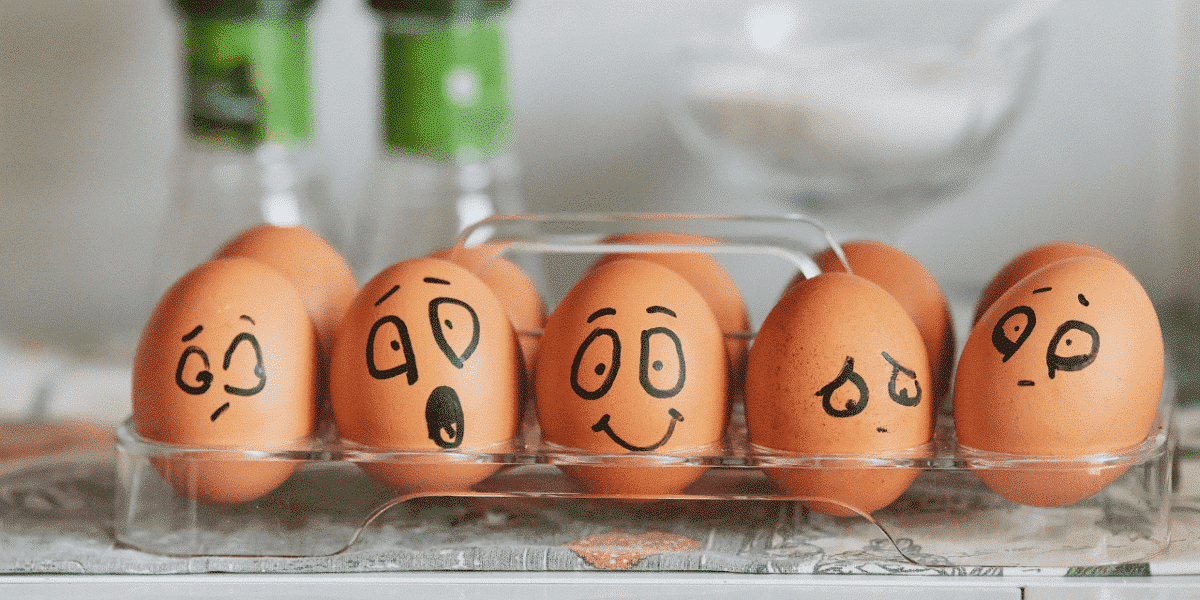Eggs in a tray with faces drawn on them showing different emotions, from surprised to happy to sad