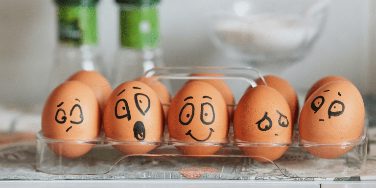 Eggs in a tray with faces drawn on them showing different emotions, from surprised to happy to sad