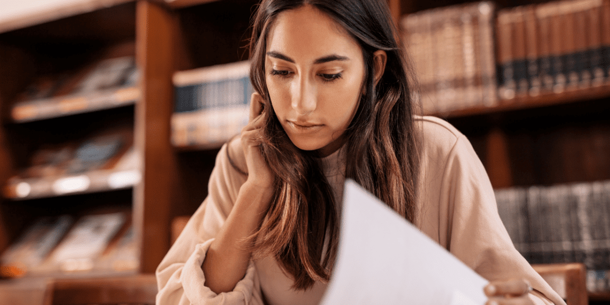 A woman in a library, reading a book and doing research