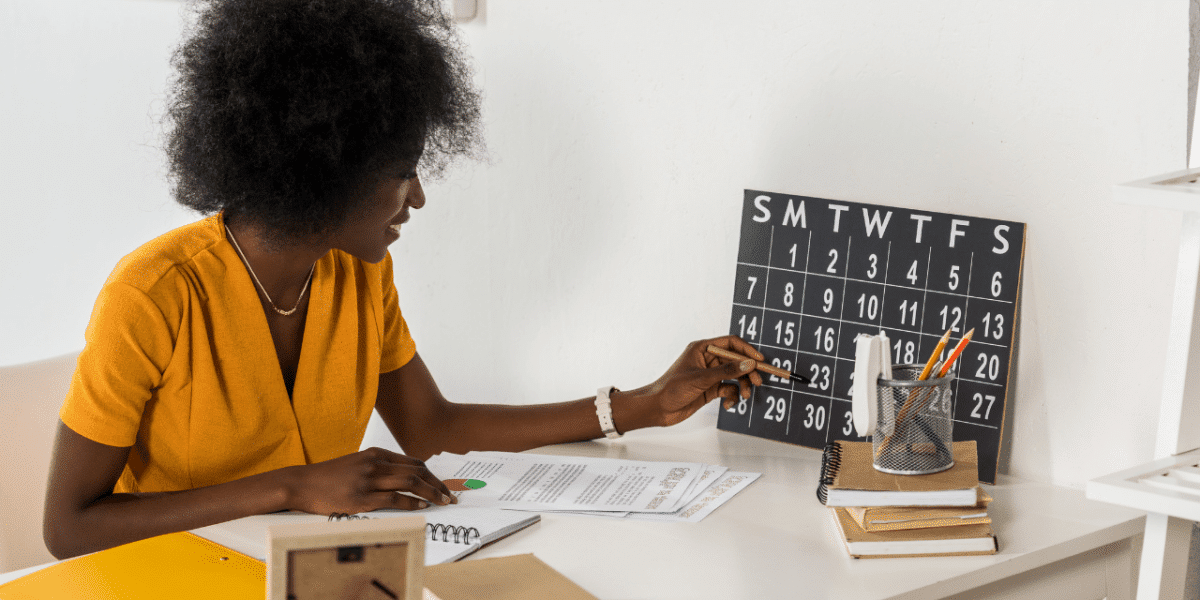 A woman checking a desk calendar and making notes