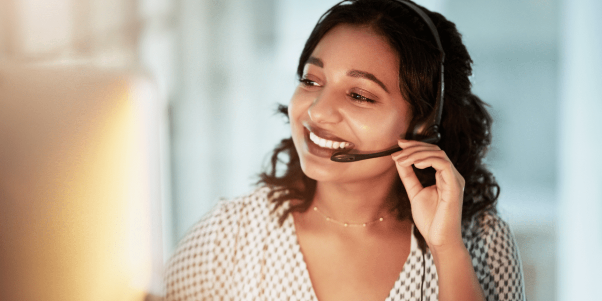 A telesales employee on the phone, using a headset. She is smiling during her conversation with the customer.