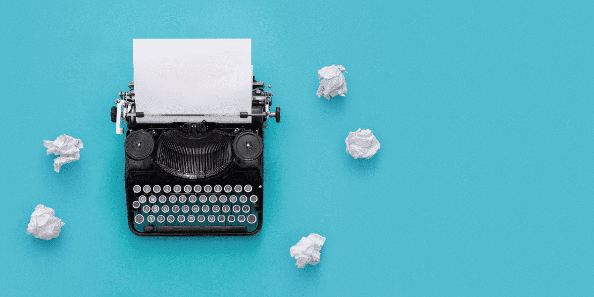 typewriter on a blue background with scrunched up paper surrounding