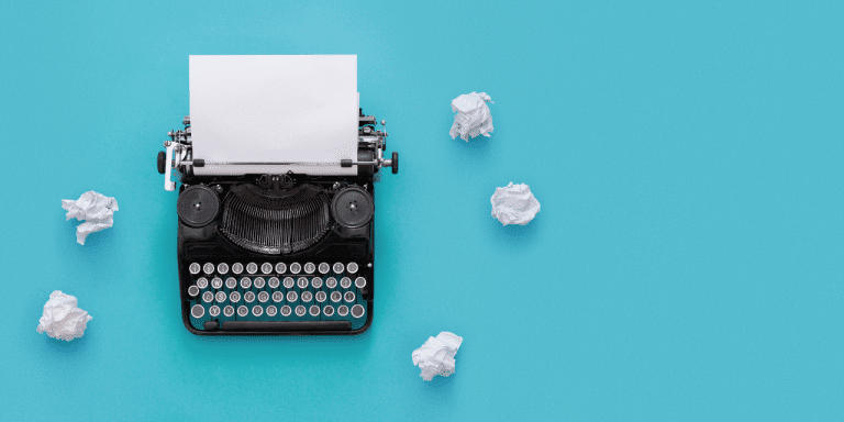 typewriter on a blue background with scrunched up paper surrounding