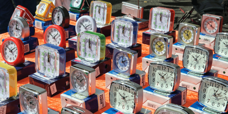 Rows of colourful alarm clocks on display at a market stall
