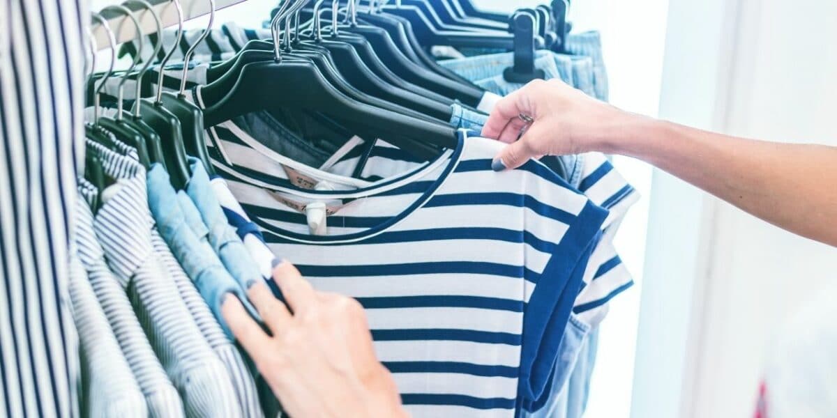 A rail of clothes, with someone going through them