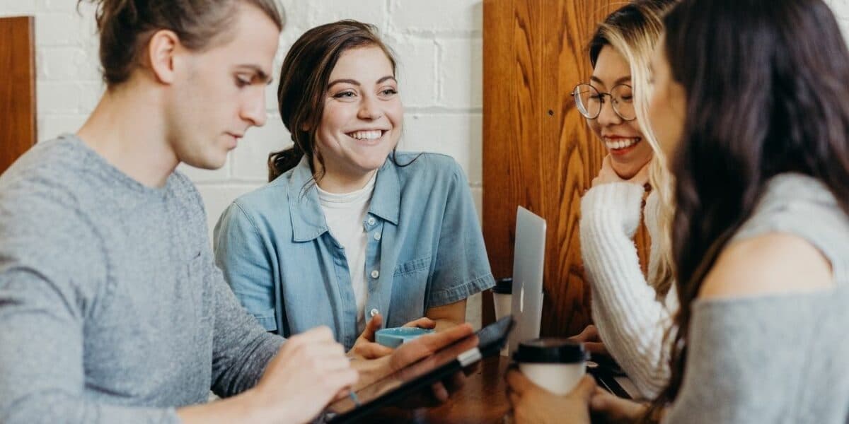 Four young adults laughing and chatting over a coffee