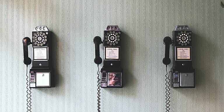 A shot of a wall with 3 old fashioned telephones in a row