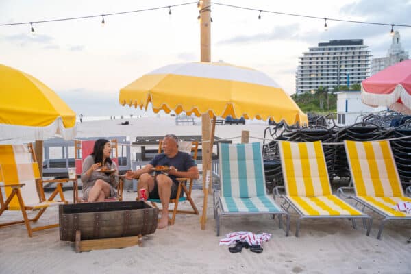 Two TextExpander employees sit together at the beach having lunch.