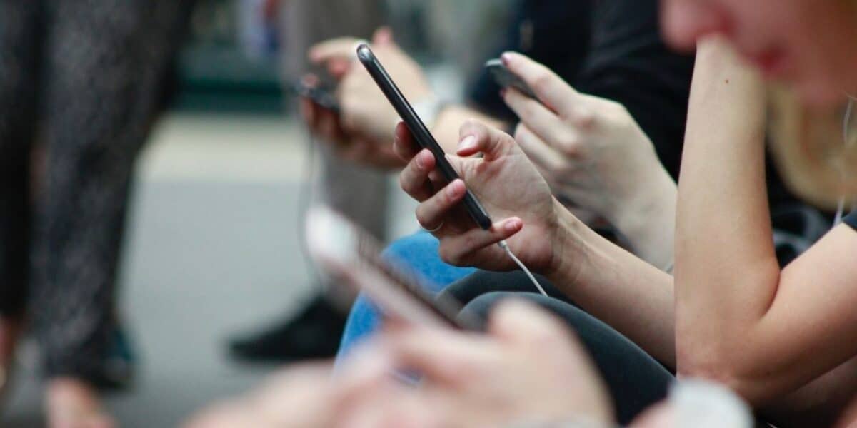 Row of people scrolling on their smartphones, illustrating text, email and DM communication