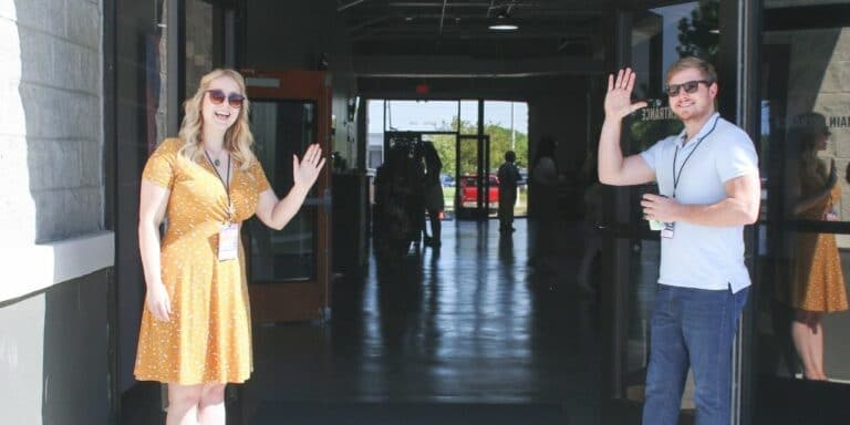 Two people wave hello at the door showing they are civil in the workplace
