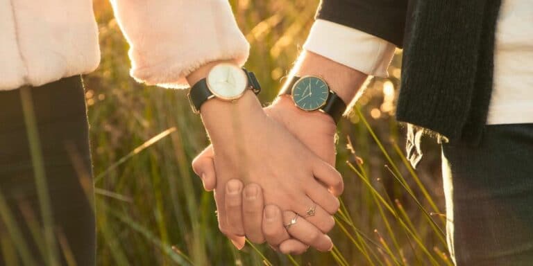 Hands holding, wearing watches