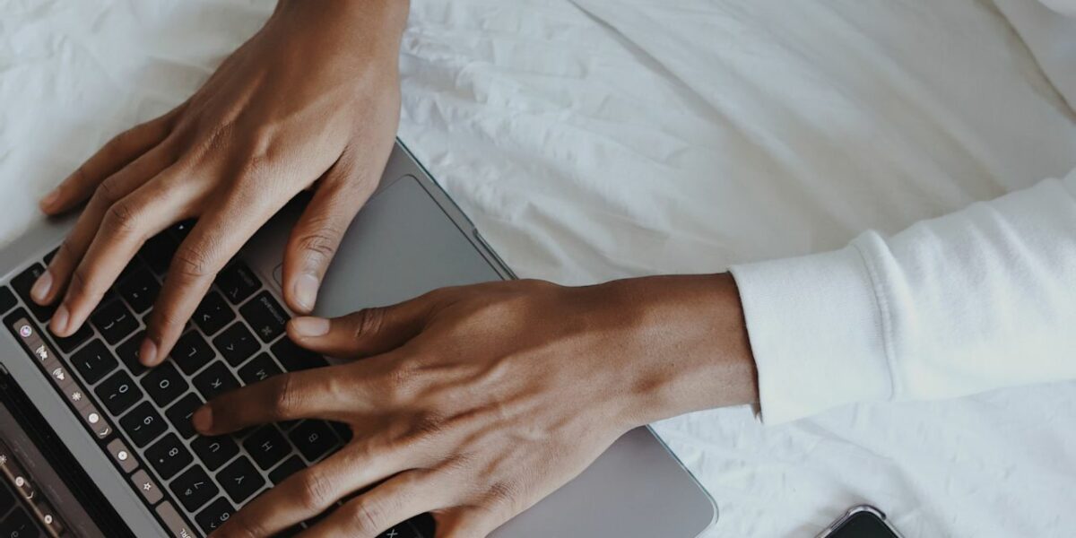 A POC's hands typing on a macbook 