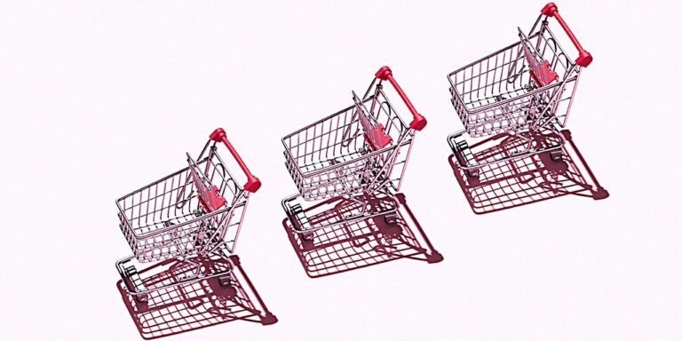 A pink background with three shopping carts lined up on top. They have heavy shadow casting next to them but the image is bright.