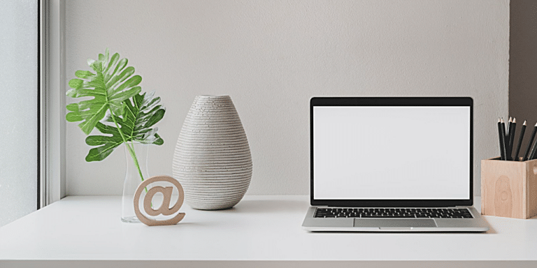 a desk with an open laptop and a wooden @ statue