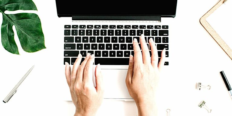 A birds-eye view of a laptop with hands in view, typing